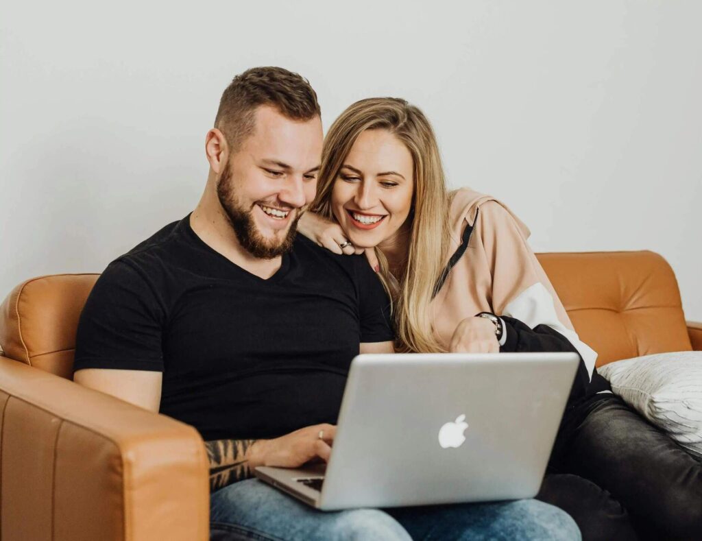 Smiling couple using a laptop at home to explore financing options with DH Fence Pros
